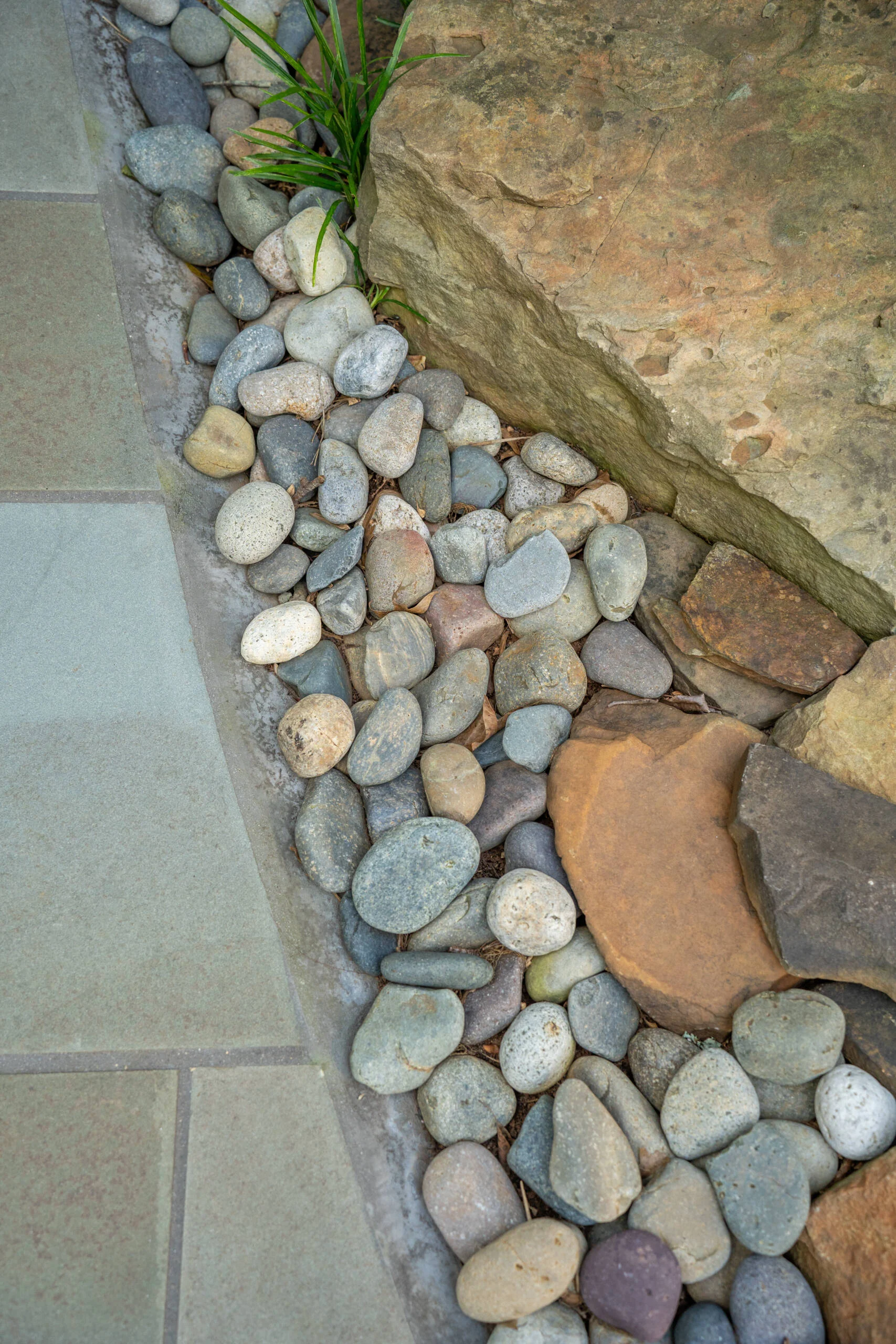 Close-up of Mexican beach pebbles bordering bluestone patio tiles, a hardscape detail from a Greenville, SC courtyard refresh
