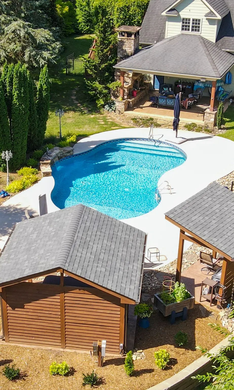 Landscape projects Greenville SC aerial view featuring custom pool with concrete surround, pergola-covered seating, and integrated outdoor structures